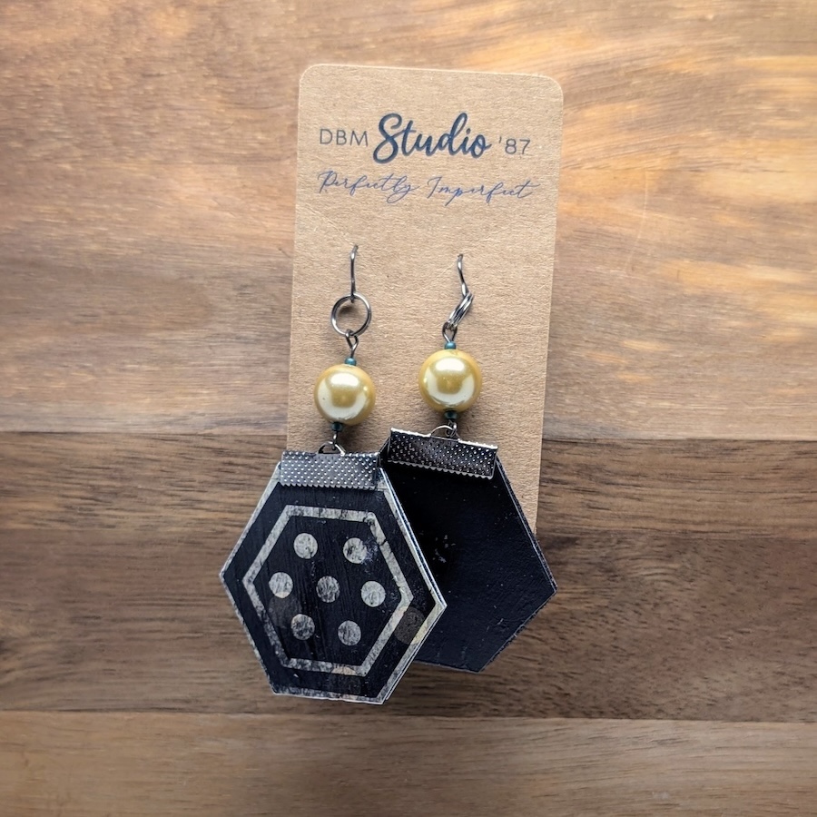These medium octagon earrings feature a felt core, a durable Mod Podged finish, black polka‑dot and solid black designs, and are accented with black metal hardware and pearled beads for a lightweight, chic, and sophisticated accessory.